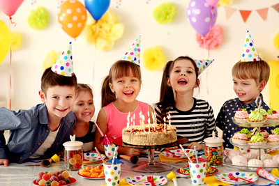 Children celebrating a birthday with cake and party decorations