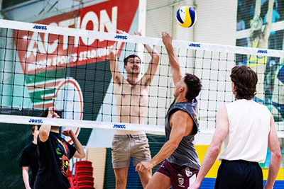Indoor beach volleyball players reaching at the net