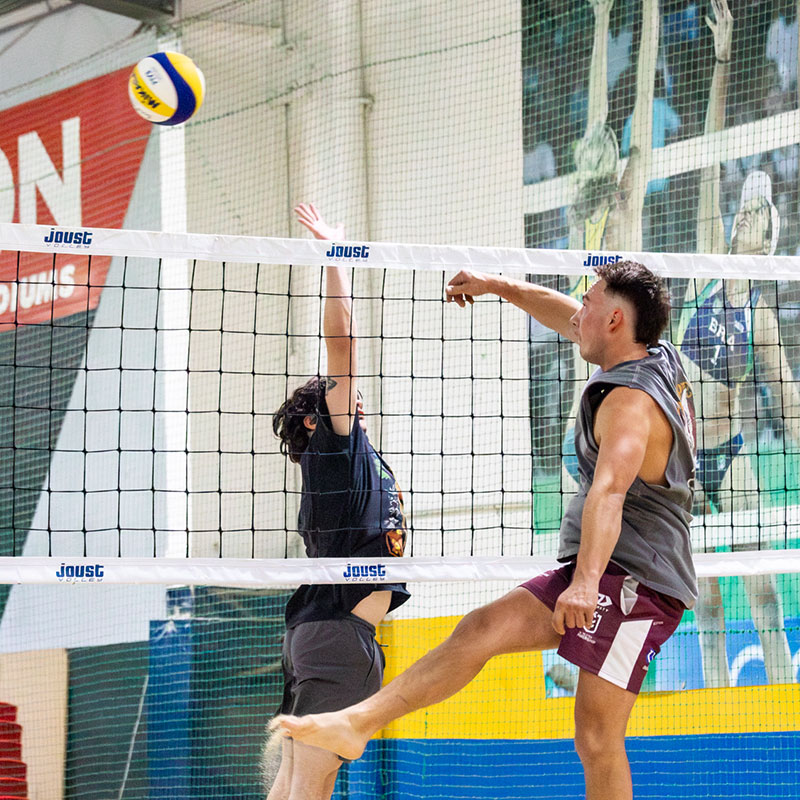 Indoor beach volleyball players at the net