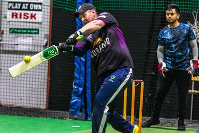 Cricket player batting inside an indoor court