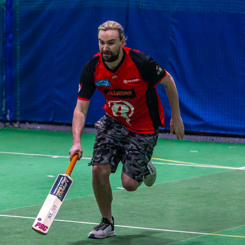 Cricket player holding a bat on an indoor court