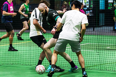 Soccer players challenging for the ball on an indoor court