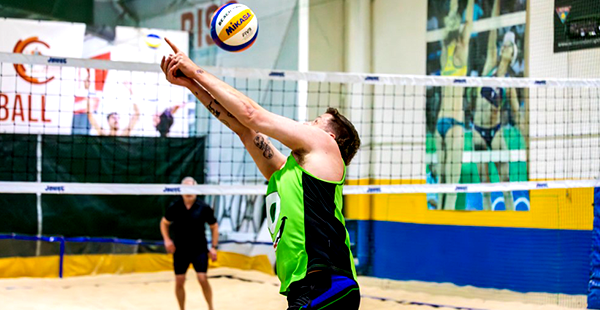 Volleyball player reaching to hit the ball at the net